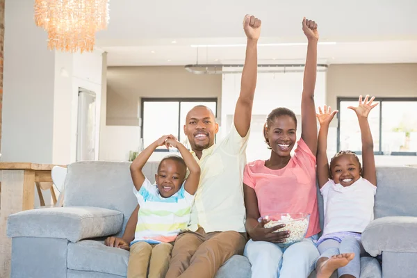 Felice famiglia guardando la televisione mangiare popcorn — Foto Stock