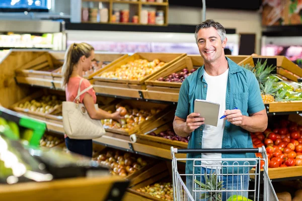 Homem sorridente segurando a lista de compras — Fotografia de Stock