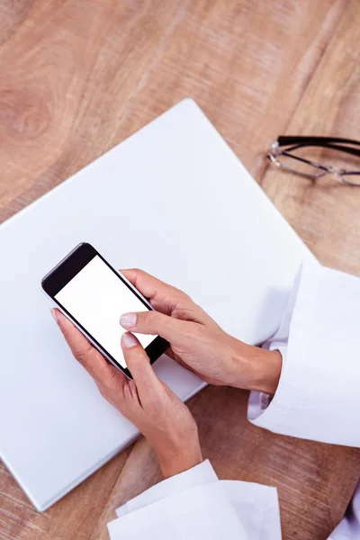 Arzt mit Smartphone auf Holztisch — Stockfoto