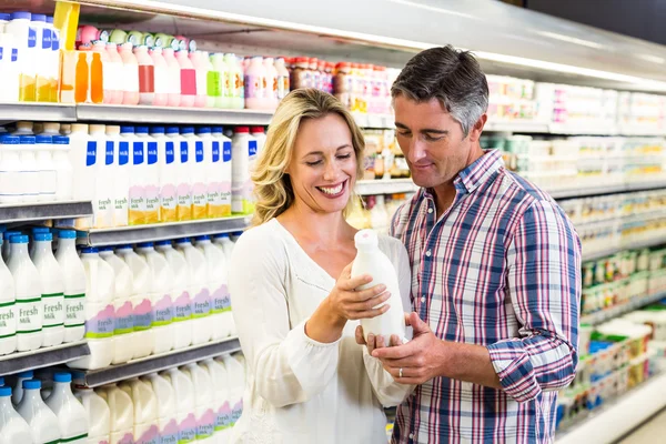 Улыбающаяся пара покупает молоко — стоковое фото