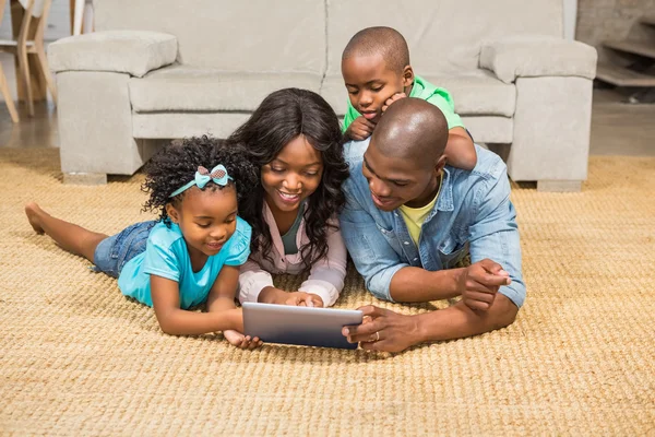 Família feliz deitada no chão usando tablet — Fotografia de Stock