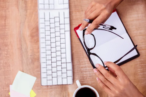 Businesswoman holding pen and eye glasses — Stock Photo, Image