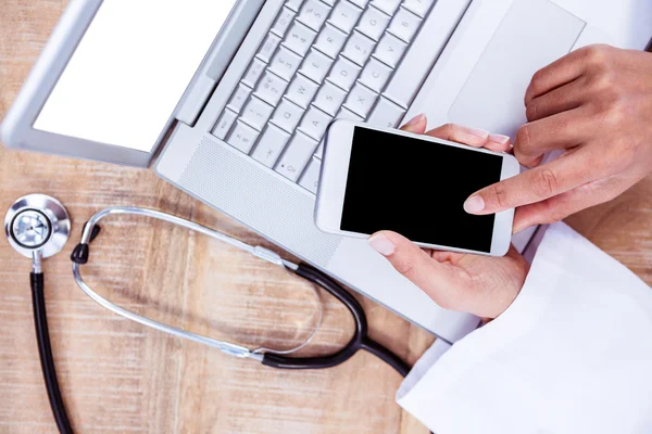 Doctor usando smartphone en escritorio de madera —  Fotos de Stock