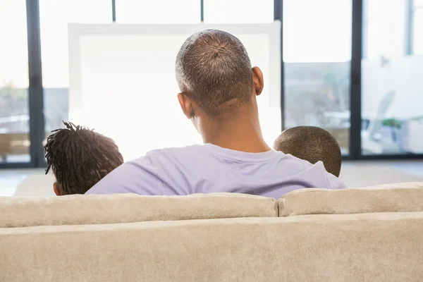 Двоє дітей сидять на дивані з батьком — стокове фото