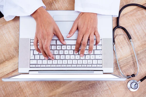 Médico usando laptop na mesa de madeira — Fotografia de Stock