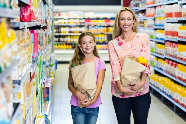 Улыбающиеся мать и дочь с пакетами продуктов — стоковое фото