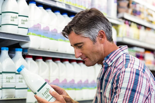 Pohledný muž v supermarketu, při pohledu na láhev mléka — Stock fotografie