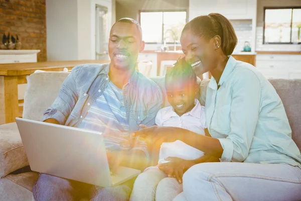 Familia feliz usando el portátil en el sofá — Foto de Stock