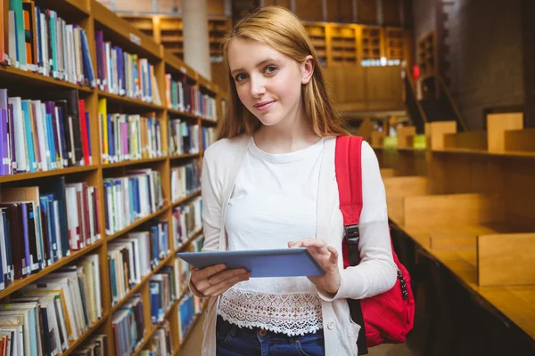 Lachende student met behulp van Tablet PC in bibliotheek rugzak — Stockfoto