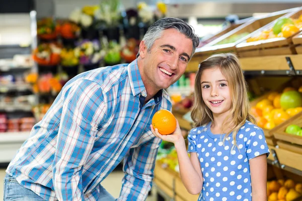 Aranyos lány gazdaság egy narancs, hogy apja — Stock Fotó