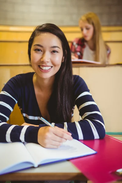 Estudante sorrindo escrevendo no caderno — Fotografia de Stock
