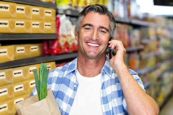 Sorrindo homem em um telefonema com saco de supermercado — Fotografia de Stock