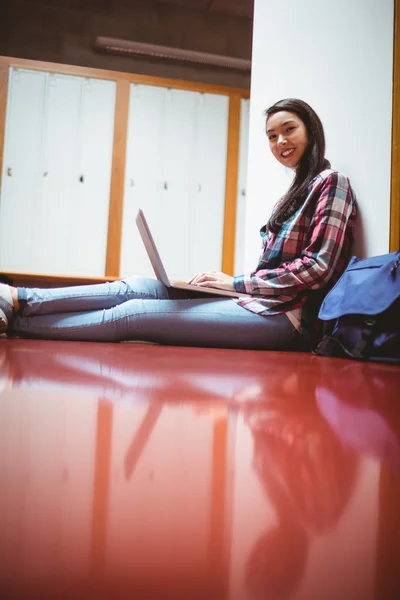 Estudante sorrindo sentado no chão e usando laptop — Fotografia de Stock