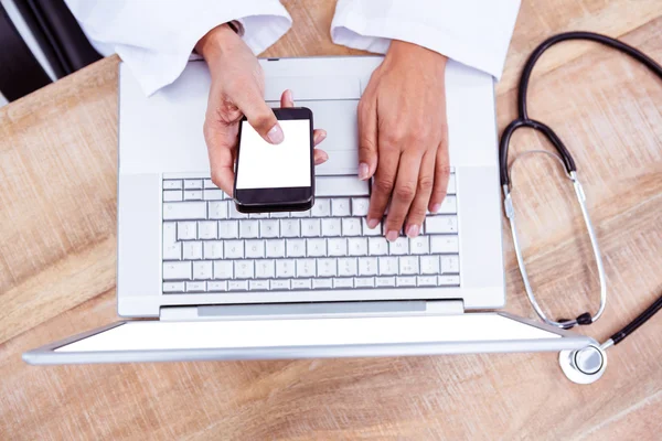 Läkare använder smartphone på trä skrivbord — Stockfoto