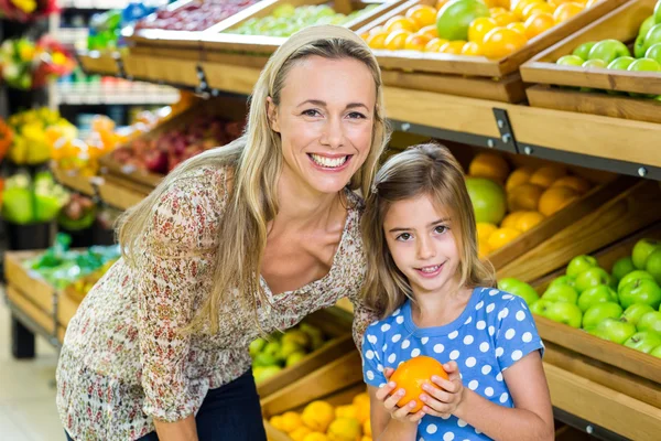Mamma med sin dotter köpa orange — Stockfoto