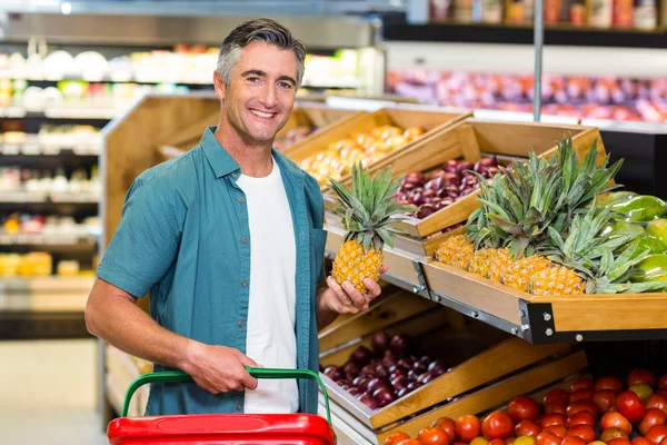 Hombre sonriente eligiendo piña —  Fotos de Stock