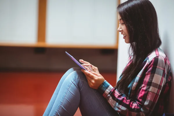 Estudiante sonriente sentado en el suelo y usando la tableta —  Fotos de Stock