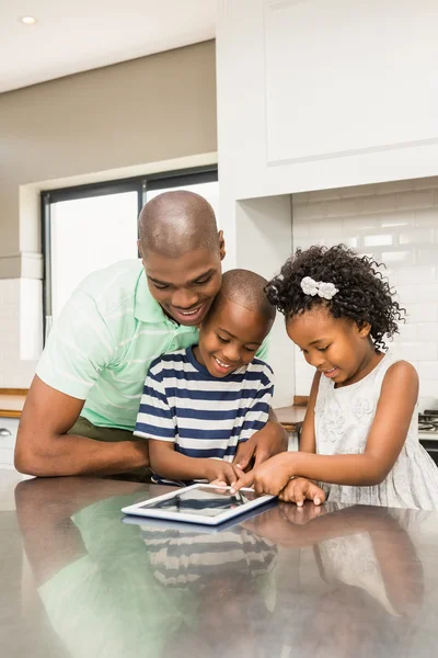 Pai usando tablet com seus filhos na cozinha — Fotografia de Stock