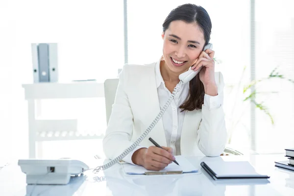 Glimlachende zakenvrouw via haar telefoon — Stockfoto