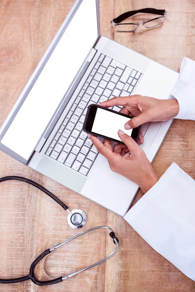 Doctor usando smartphone en escritorio de madera —  Fotos de Stock