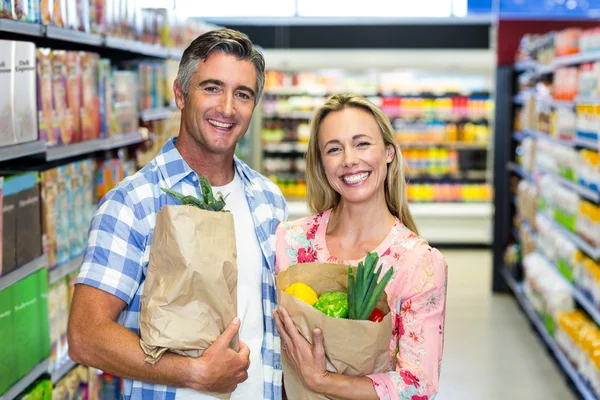 Pareja sonriente con bolsas de comestibles — Foto de Stock