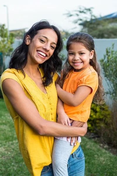 Mãe de pé segurando sua filha ao ar livre — Fotografia de Stock