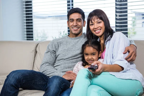 Leende familjen tittar på tv i soffan — Stockfoto