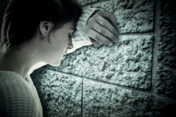 Composite image of sad pretty brunette leaning against wall — Stock Photo, Image