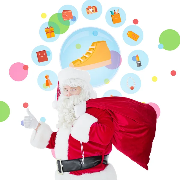Positieve santa met zijn zak en duimschroef opwaarts — Stockfoto