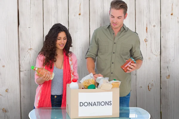 Добровольцы достают еду из коробки с пожертвованиями — стоковое фото