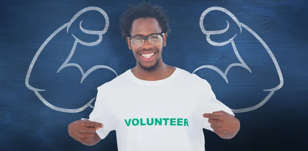 Bonito homem apontando para sua camiseta voluntária — Fotografia de Stock