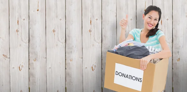 Mujer con donación de ropa haciendo gestos con los pulgares hacia arriba — Foto de Stock