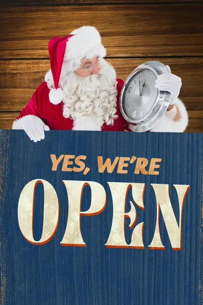 Zusammengesetztes Bild des Weihnachtsmannes mit Uhr und Schild — Stockfoto