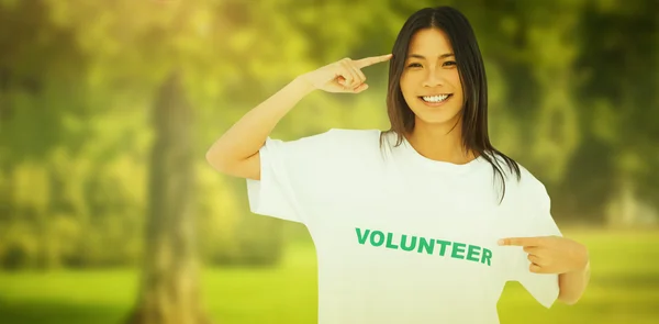 Leende kvinna som pekar på hennes volontär tshir — Stockfoto