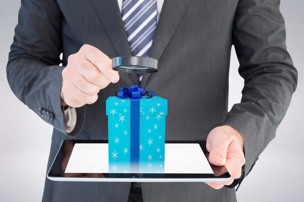 Businessman looking at tablet with magnifying glass — Stock Photo, Image