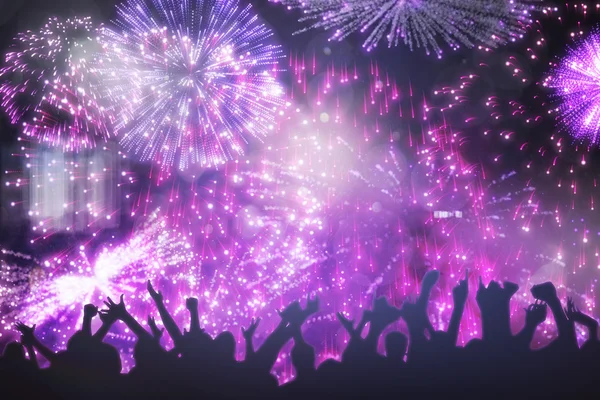 Silhuetas comemorando contra fogos de artifício coloridos — Fotografia de Stock