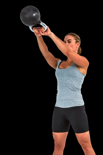 Serious muscular woman lifting kettlebell — Stock Photo, Image