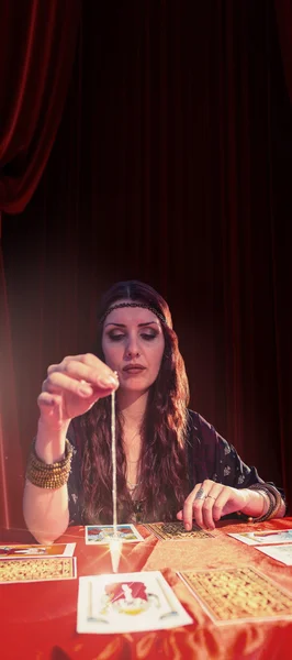 Female fortune teller looking at pendulum — Stock Photo, Image