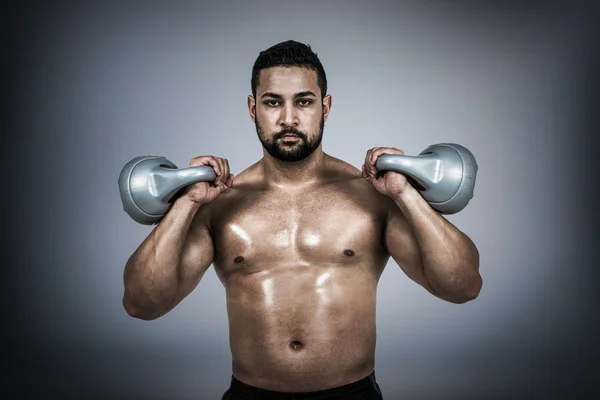 Homem muscular levantando kettlebell pesado — Fotografia de Stock