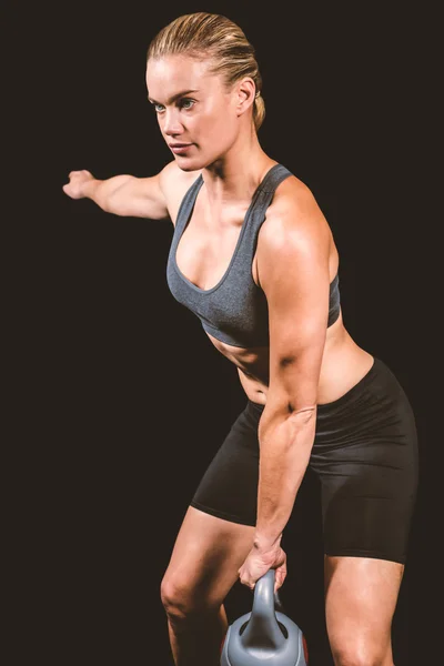 Mulher muscular balançando kettlebell pesado — Fotografia de Stock
