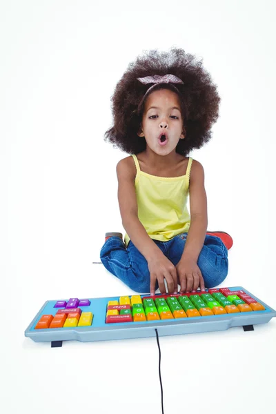 Cute girl sitting on the floor using colored keybord — Stock Photo, Image