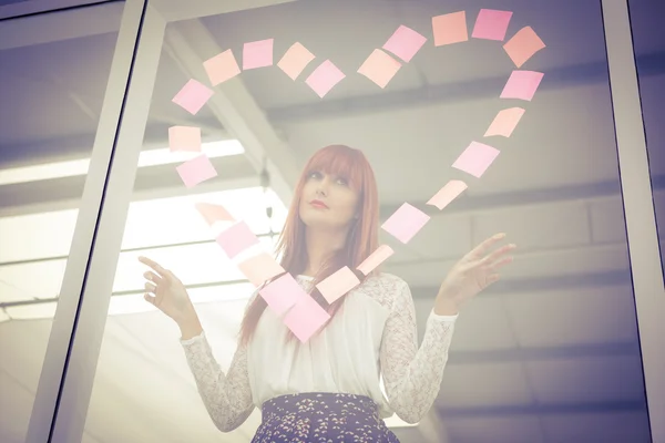 Donna hipster sorridente che fa un cuore nel post-it — Foto Stock