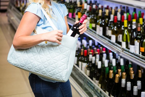 Frau steckt Weinflasche in Tüte — Stockfoto