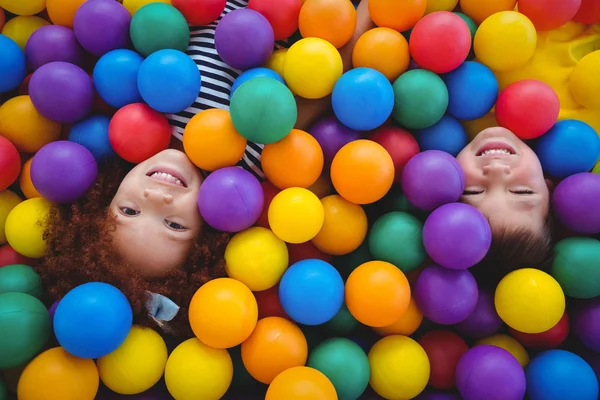 Lindos niños sonrientes en piscina de bolas de esponja —  Fotos de Stock