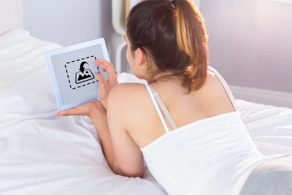 Mujer relajada usando tableta digital en la cama —  Fotos de Stock