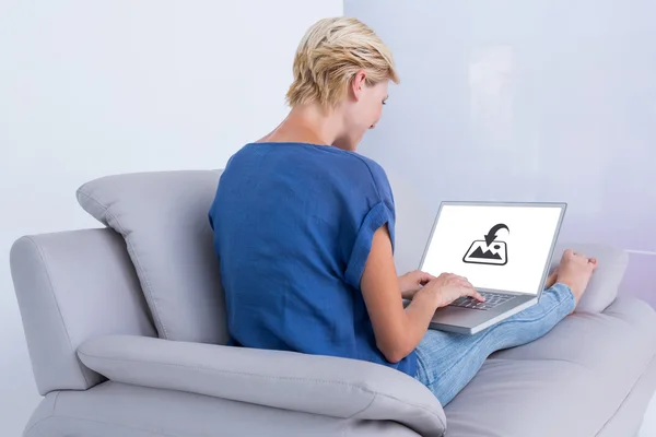 Mulher loira usando seu laptop no sofá — Fotografia de Stock