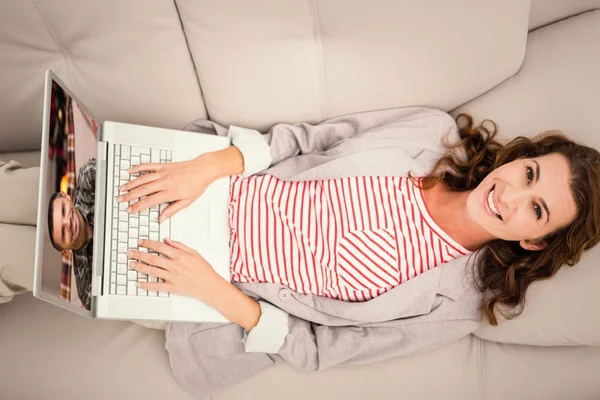 女人躺在沙发上时使用的笔记本电脑 — 图库照片