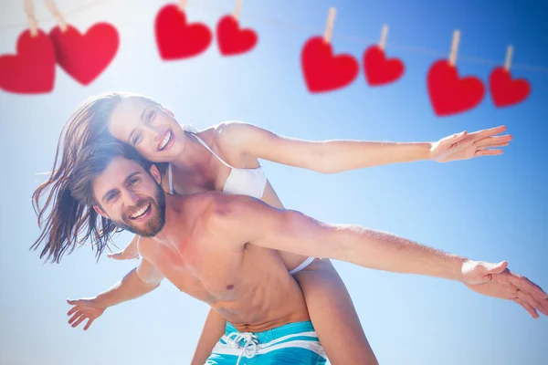 Handsome man giving piggy back to his girlfri — Stock Photo, Image