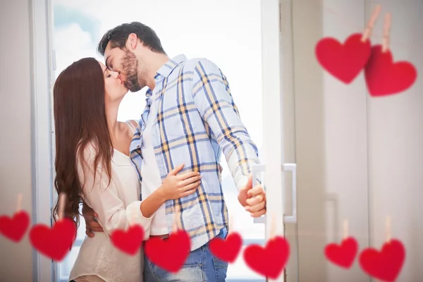 Jovem casal beijo como eles abrem a porta da frente — Fotografia de Stock