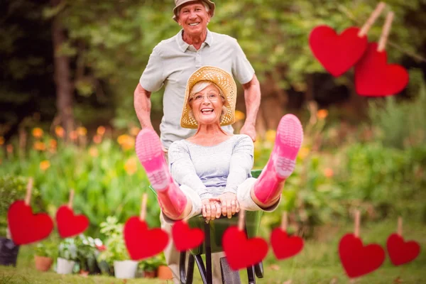 Felice coppia di anziani che gioca con un wheelbarro — Foto Stock